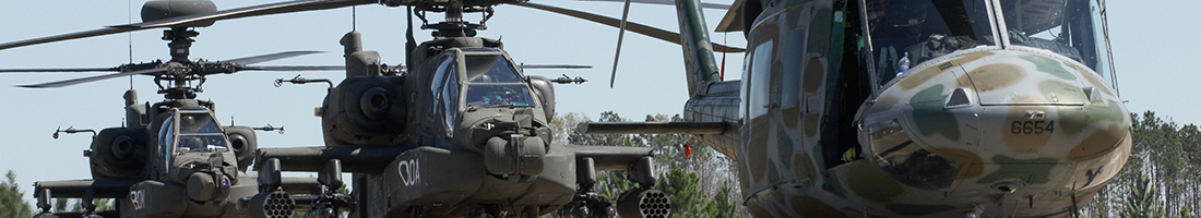 A set of three Apache helicopters sit on the helipad